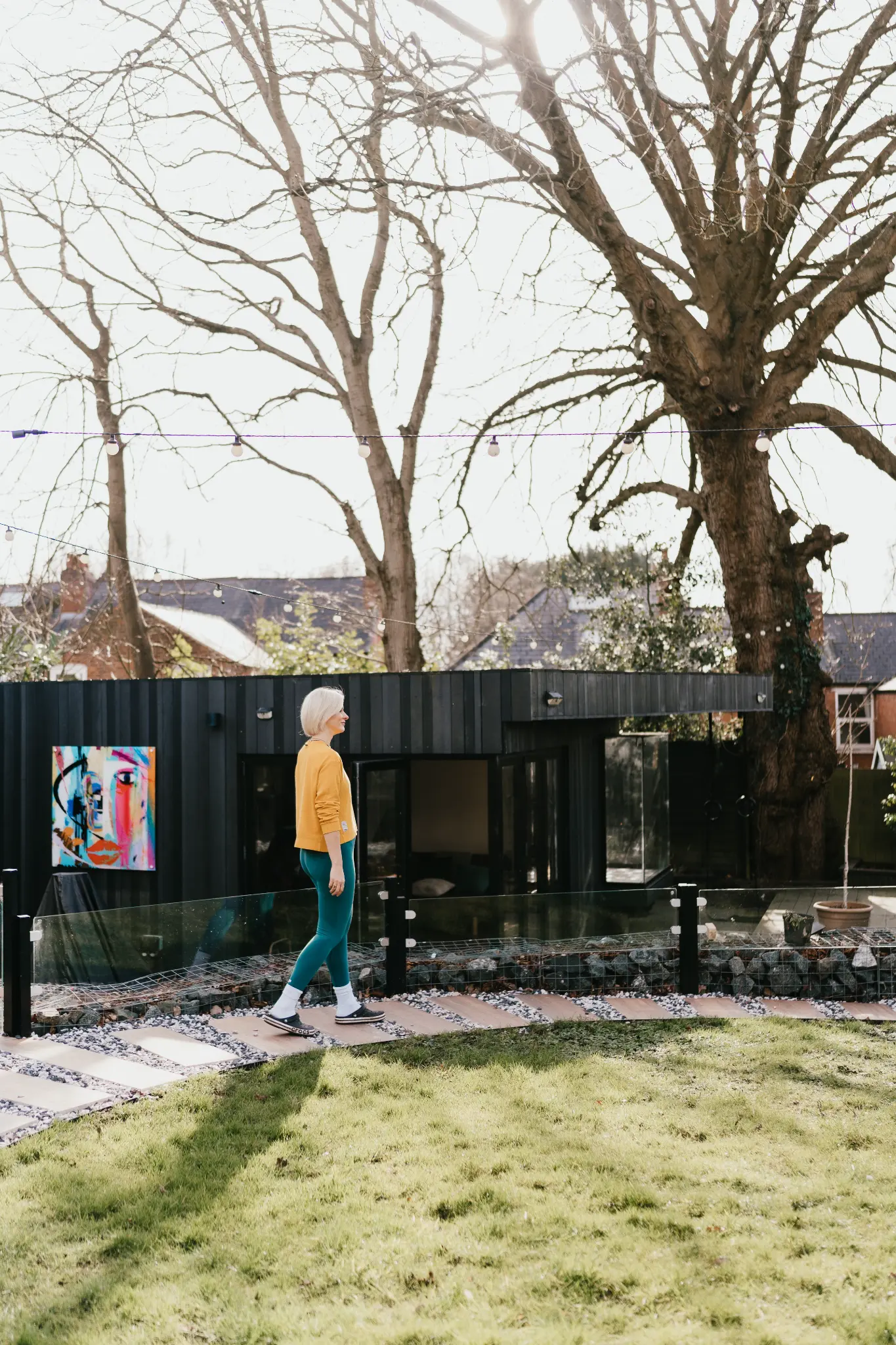 Lucy Nash standing in a garden with colourful artwork behind her