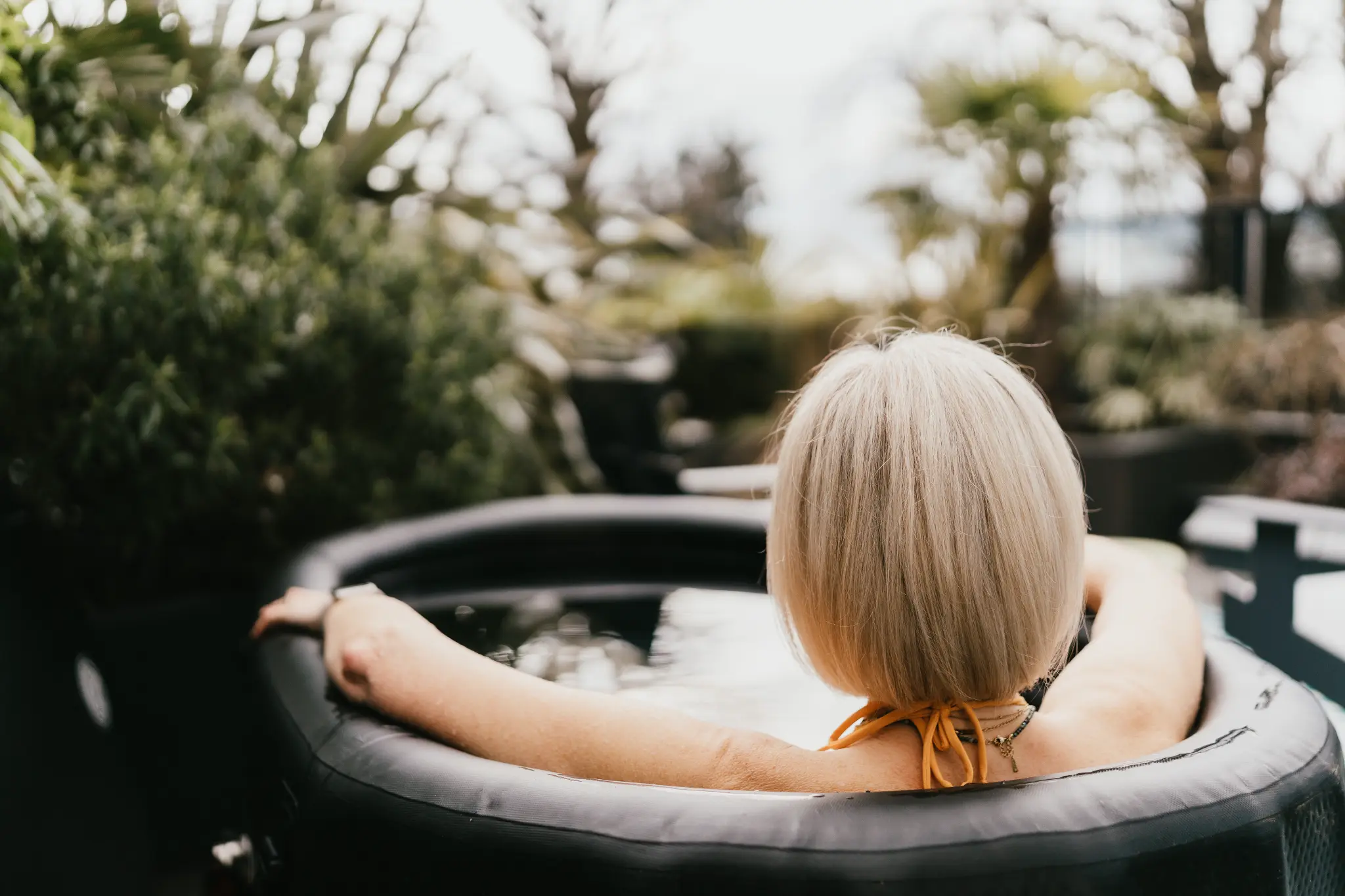 Lucy Nash sitting quietly in a hot tub, seen from behind
